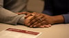 Couples' hands overlapped on desk